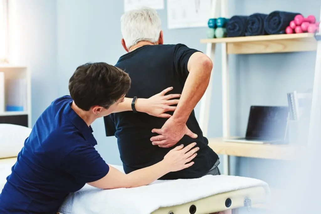 Physical therapist assessing a patient's lower back and spine