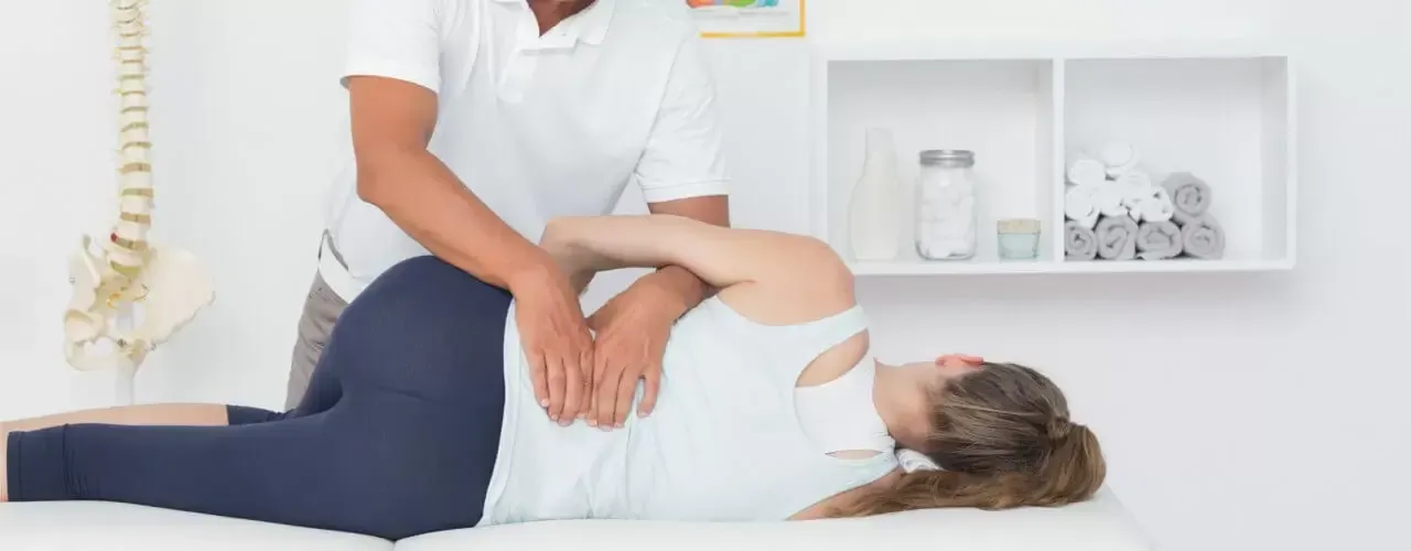 Physical therapist assessing a patient's lower back and spine